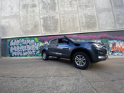 Gray pickup truck with stainless steel snorkel parked in front of graffiti wall