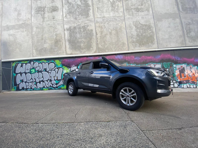 Gray pickup truck with stainless steel snorkel parked in front of graffiti wall