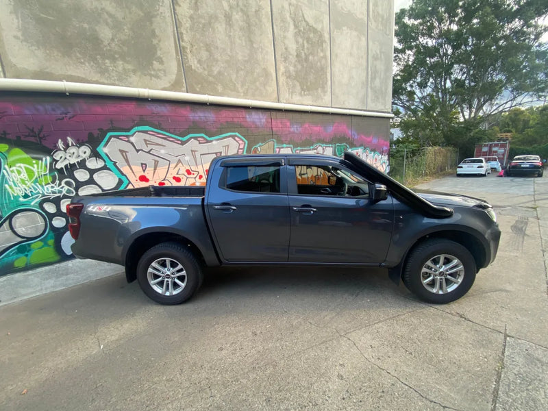 Gray pickup truck with stainless steel snorkel parked next to graffitied wall