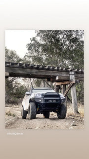 Modified off-road truck with oversized tires under wooden structure showcasing Stainless Steel Snorkel Kit