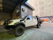 Modified pickup truck with oversized off-road tires and a flatbed featuring stainless steel snorkel