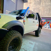 Off-road pickup with oversized tires and light green body, featuring Meredith stainless steel snorkel kit