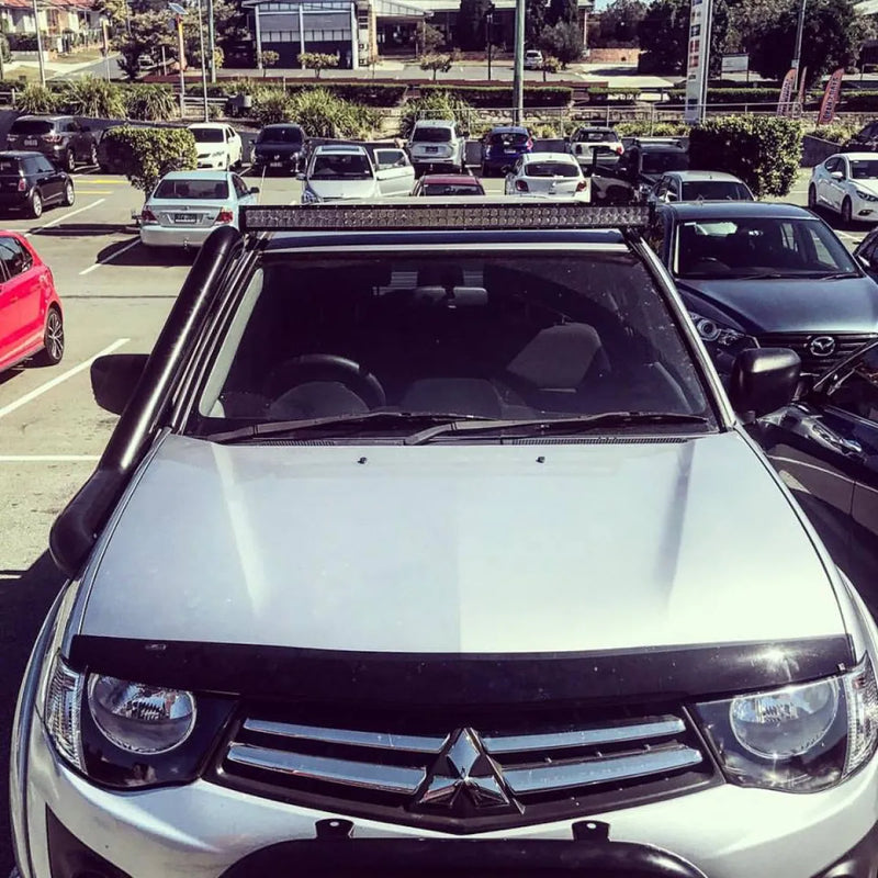 Silver Mitsubishi pickup truck with steel snorkel and roof-mounted light bar