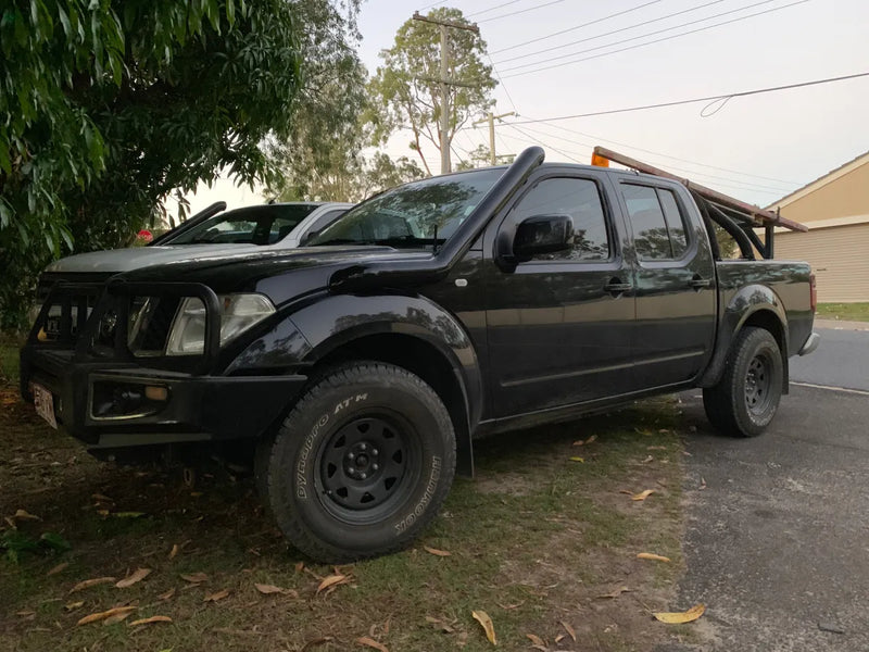 Black off-road pickup with oversized tires and damaged front end, featuring a stainless steel snorkel
