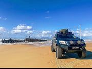 Off-road vehicle with stainless steel snorkel parked on sandy beach beach scene