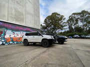 White SUV parked beside a graffiti wall showcasing Meredith stainless steel snorkel kit for Toyota Prado