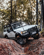 White Toyota Land Cruiser with stainless steel snorkel off-road modifications on rugged terrain