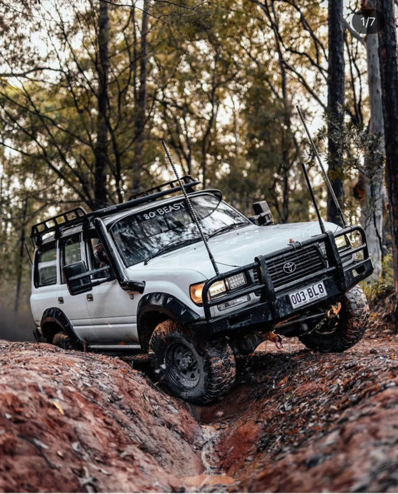 White Toyota Land Cruiser with stainless steel snorkel off-road modifications on rugged terrain