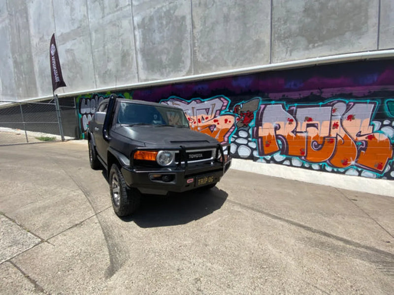 Black Toyota FJ Cruiser with stainless steel snorkel parked near graffiti wall