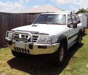 White Nissan Patrol GU Y61 SUV with bull bar and roof rack featuring extendable towing mirrors