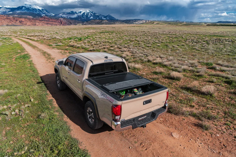 Pickup truck with UnderCover Ultra Flex hard folding tonneau cover on dirt road in rural landscape