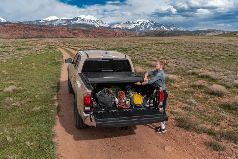 ULTRA FLEX hard folding truck bed cover on pickup truck with open tailgate loaded with camping gear