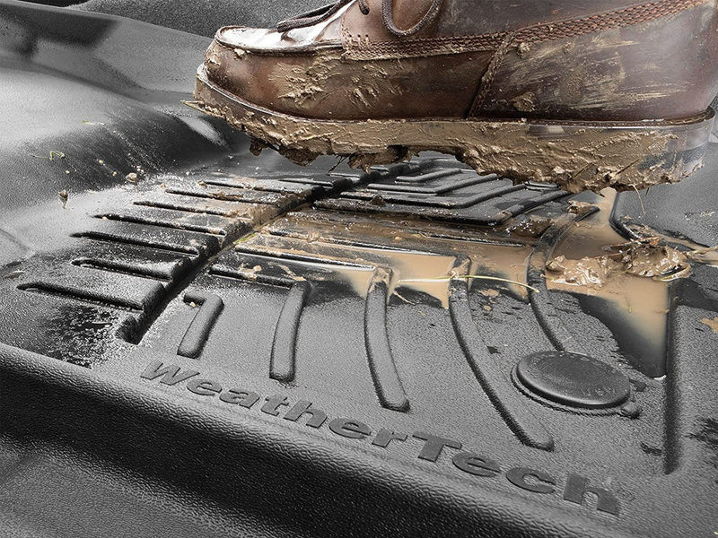 WeatherTech high performance front and rear floor mats being stepped on by a muddy boot